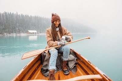 穿着棕色夹克和蓝色牛仔牛仔裤的男人白天坐在棕色的木船上
